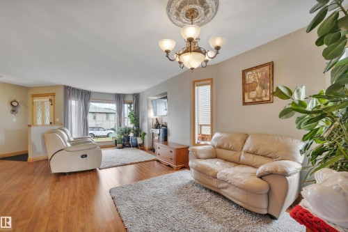 Wood-finish flooring, bay window, chandelier with decorative ceiling medallion, and neutral wall tones - 4224 53 Ave, Wetaskiwin, AB - Indoor Photo Showing Living Room