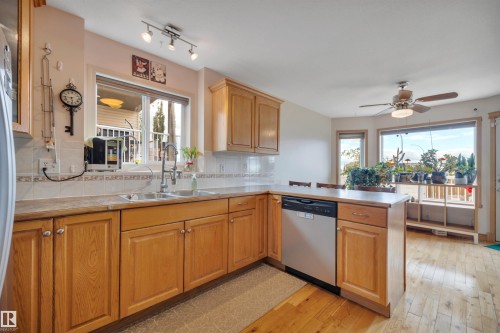 Kitchen featuring wood-finish cabinetry, stainless steel dishwasher, double basin sink, and track lighting - 4224 53 Ave, Wetaskiwin, AB - Indoor Photo Showing Kitchen With Double Sink