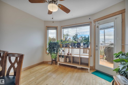 Hardwood-style flooring, ceiling fan with integrated lighting, multiple windows, and a glass-paneled door - 4224 53 Ave, Wetaskiwin, AB - Indoor Photo Showing Other Room