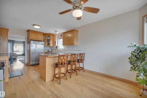 Kitchen featuring wood-finish flooring, wood cabinetry, stainless steel refrigerator, and a ceiling fan with integrated lighting - 4224 53 Ave, Wetaskiwin, AB - Indoor Photo Showing Kitchen