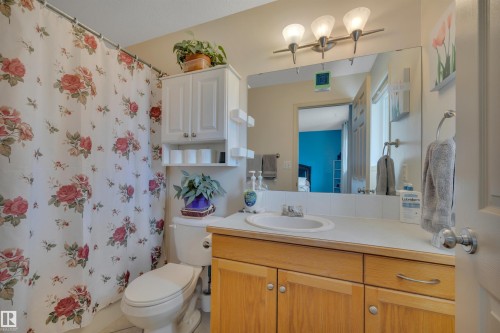 Bathroom with a neutral color palette, wood-finish vanity, integrated sink, and wall-mounted light fixture - 4224 53 Ave, Wetaskiwin, AB - Indoor Photo Showing Bathroom