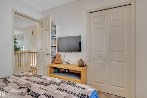 White wall paint, light-colored bi-fold closet doors, and wood-finish flooring - 4224 53 Ave, Wetaskiwin, AB - Indoor Photo Showing Bedroom