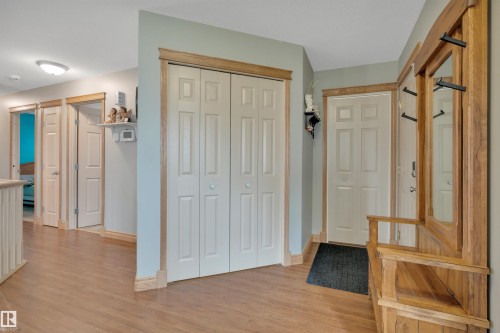 Wood-finish flooring throughout, white interior doors with wood trim, and a built-in wooden hall tree with mirror - 4224 53 Ave, Wetaskiwin, AB - Indoor Photo Showing Other Room