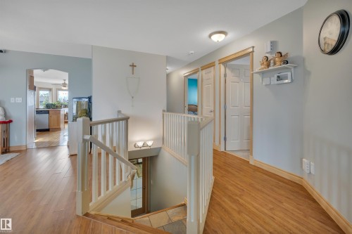 Wood-finish flooring throughout the hallway, white painted stair railings, and light wall tones - 4224 53 Ave, Wetaskiwin, AB - Indoor Photo Showing Other Room