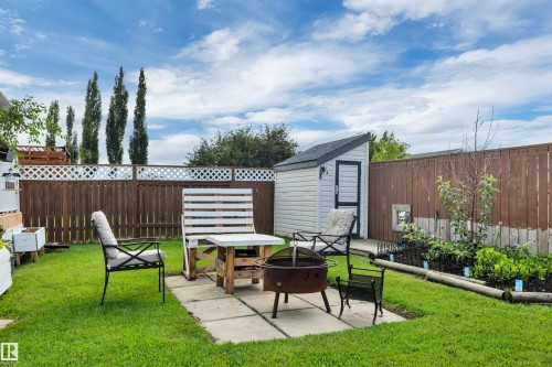 Expansive backyard featuring a manicured lawn, a concrete patio area, a wood privacy fence with lattice detailing, a garden shed, and planted garden beds - 4224 53 Ave, Wetaskiwin, AB - Outdoor With Deck Patio Veranda