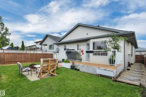 Backyard featuring a wooden privacy fence, a raised wood deck with white railings, and a concrete patio area - 4224 53 Ave, Wetaskiwin, AB - Outdoor With Deck Patio Veranda