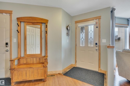 Entryway featuring a decorative front door with leaded glass panels, wood-finish flooring, and light-toned wall paint - 4224 53 Ave, Wetaskiwin, AB - Indoor Photo Showing Other Room