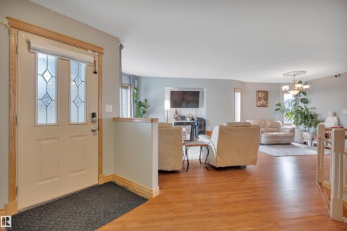 Entry door with decorative glass inserts, wood-finish flooring, and a half-wall partition - 4224 53 Ave, Wetaskiwin, AB - Indoor