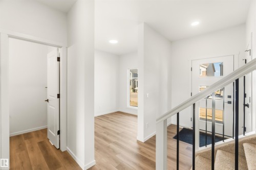 Entryway featuring a contemporary front door with multiple glass panes, wood-finish flooring, a neutral color palette, recessed lighting, and a staircase with a white handrail and black balusters - 265 Chappelle Drive Sw, Edmonton, AB - Indoor Photo Showing Other Room