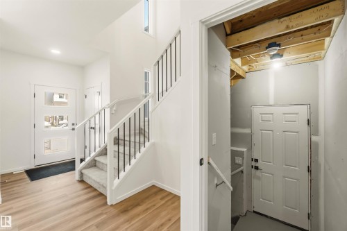 Entryway featuring wood-finish flooring, a contemporary staircase with black spindles and carpeted treads, and an exterior door with frosted glass panels - 265 Chappelle Drive Sw, Edmonton, AB - Indoor Photo Showing Other Room