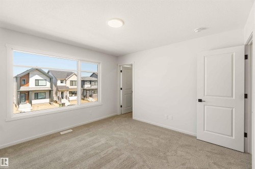 Spacious bedroom featuring light-colored carpeting, white painted walls, and a large multi-pane window - 265 Chappelle Drive Sw, Edmonton, AB - Indoor Photo Showing Other Room