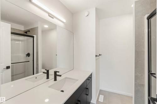 Modern bathroom featuring a dual vanity with a white countertop and dark cabinetry - 265 Chappelle Drive Sw, Edmonton, AB - Indoor
