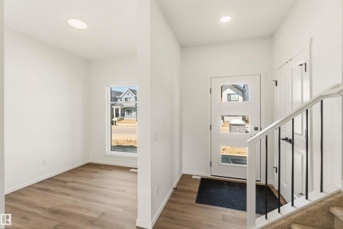 Entryway featuring a modern door with rectangular lites, wood-finish flooring, recessed lighting, and a staircase with white newel posts and black iron balusters - 265 Chappelle Drive Sw, Edmonton, AB - Indoor Photo Showing Other Room