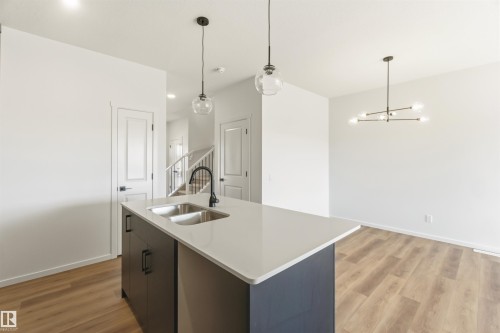 Kitchen island featuring a double basin stainless steel sink, black gooseneck faucet, and light quartz-style countertop - 265 Chappelle Drive Sw, Edmonton, AB - Indoor Photo Showing Kitchen With Double Sink With Upgraded Kitchen