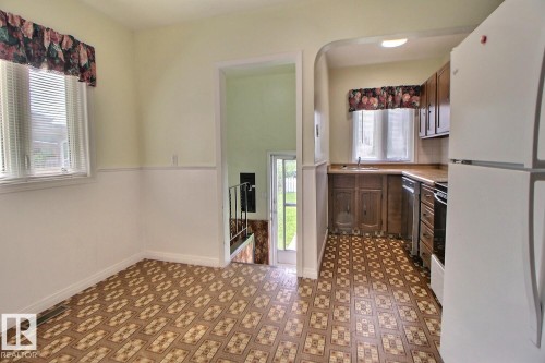 Kitchen with wood-finish cabinetry, a stainless steel dishwasher, and a white refrigerator - 11336 83 Street Nw, Edmonton, AB - Indoor