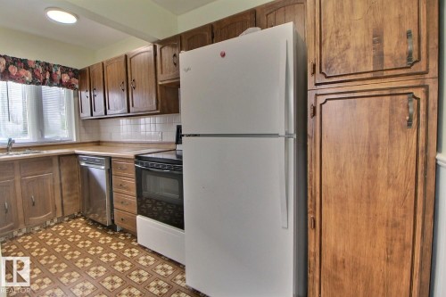 Kitchen with wood-finish cabinetry, patterned floor tiles, white tile backsplash, and a built-in dishwasher - 11336 83 Street Nw, Edmonton, AB - Indoor Photo Showing Kitchen