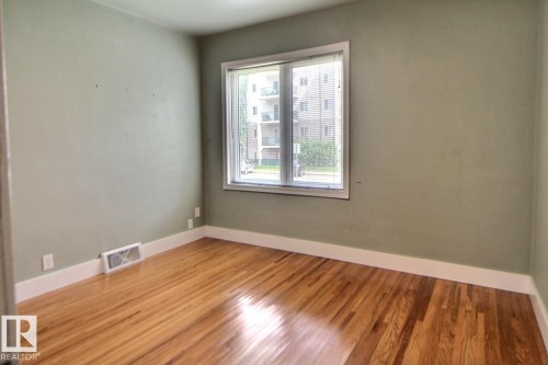 Wood-finish flooring, neutral wall color, and a large window with white trim - 11336 83 Street Nw, Edmonton, AB - Indoor Photo Showing Other Room
