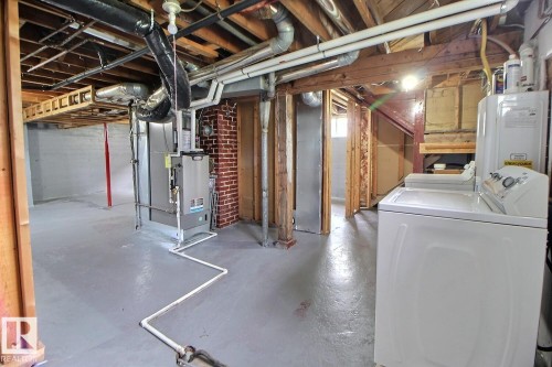 Unfinished basement with a concrete floor, exposed ceiling joists, and a brick chimney - 11336 83 Street Nw, Edmonton, AB - Indoor Photo Showing Basement