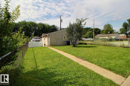 Expansive lawn with a concrete walkway, chain link fencing, a white picket gate, and mature trees - 11336 83 Street Nw, Edmonton, AB - Outdoor