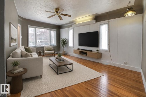 Bay window with multiple panes, wood-finish flooring, ceiling fan with integrated lighting, recessed lighting, and a floating media console - 11336 83 Street Nw, Edmonton, AB - Indoor Photo Showing Living Room