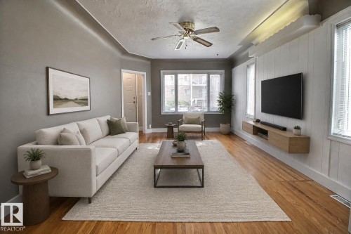Hardwood flooring, painted walls, ceiling fan, natural light from multiple windows, and a floating media console - 11336 83 Street Nw, Edmonton, AB - Indoor Photo Showing Living Room