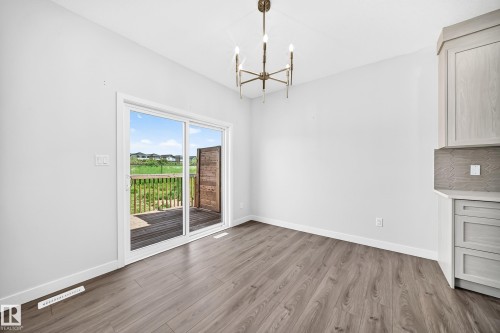 Wood-finish flooring with a sliding glass door, leading to an outdoor deck with wood railings - 8823 Carson Way Sw, Edmonton, AB - Indoor Photo Showing Other Room