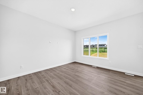 Spacious room with wood-finish flooring, white walls, and a large multi-pane window - 8823 Carson Way Sw, Edmonton, AB - Indoor Photo Showing Other Room