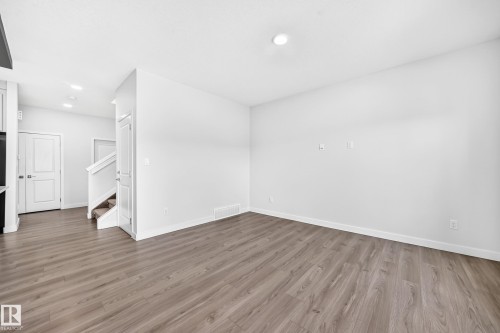 Recessed ceiling lighting, wood-finish flooring, white walls, and a staircase with carpeted treads - 8823 Carson Way Sw, Edmonton, AB - Indoor Photo Showing Other Room