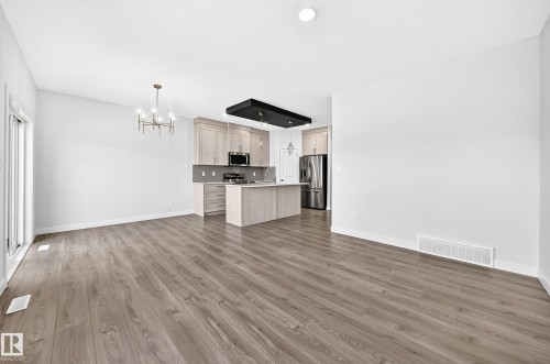 Open-concept living space featuring wood-finish flooring, a modern chandelier, and recessed lighting - 8823 Carson Way Sw, Edmonton, AB - Indoor Photo Showing Kitchen