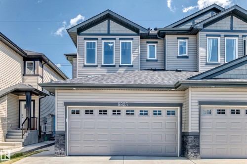 Light-colored siding with dark trim, two-car garage, multiple windows, and a covered entry - 8823 Carson Way Sw, Edmonton, AB - Outdoor With Facade