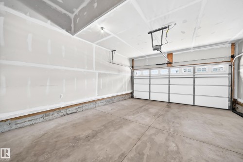 Spacious garage featuring a concrete floor, overhead lighting, and an automated garage door with upper-level windows - 8823 Carson Way Sw, Edmonton, AB - Indoor Photo Showing Garage