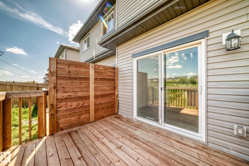 Wood-finish deck with privacy wall, sliding glass door, and exterior lighting fixture - 8823 Carson Way Sw, Edmonton, AB - Outdoor With Deck Patio Veranda With Exterior
