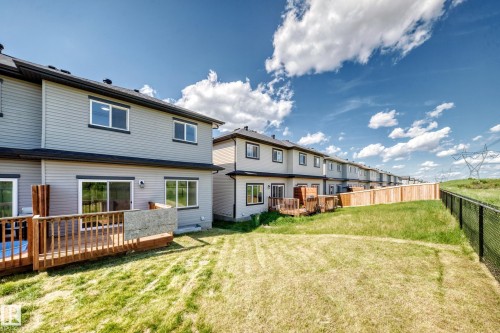 Rear exterior featuring a wood deck, sliding glass door, and multiple windows - 8823 Carson Way Sw, Edmonton, AB - Outdoor