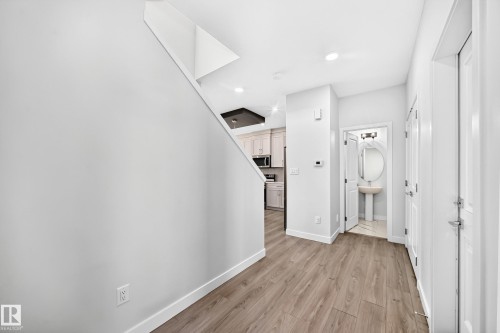 Wood-finish flooring throughout the entry, recessed ceiling lighting, and a modern half-bath with pedestal sink - 8823 Carson Way Sw, Edmonton, AB - Indoor Photo Showing Other Room