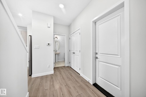 Wood-finish flooring throughout, bright white walls, and paneled doors - 8823 Carson Way Sw, Edmonton, AB - Indoor Photo Showing Other Room