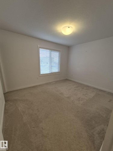 Neutral tone wall paint, flush mount ceiling light fixture, white window trim, and neutral tone carpet flooring - Edmonton, AB - Indoor Photo Showing Other Room