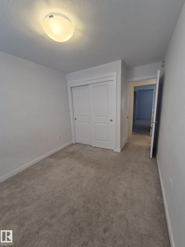 Neutral gray carpeting, white walls, flush mount ceiling lighting, and bi-fold closet doors - Edmonton, AB - Indoor Photo Showing Other Room
