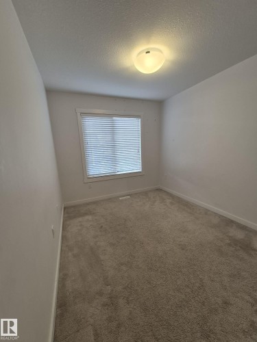 Window with horizontal blinds, flush mount ceiling light fixture, and neutral carpeting - Edmonton, AB - Indoor Photo Showing Other Room