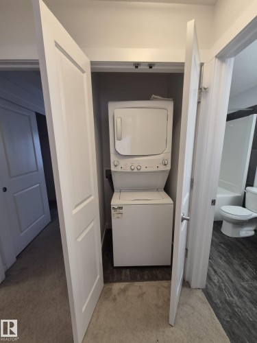 Laundry closet featuring a white stacked washer and dryer unit - Edmonton, AB - Indoor Photo Showing Laundry Room