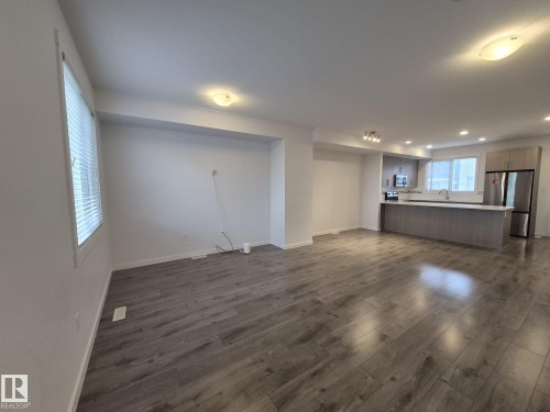 Open-concept living area with wood-finish flooring, white walls, and recessed lighting - Edmonton, AB - Indoor