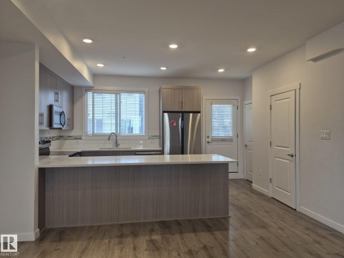 Kitchen featuring wood-finish flooring, recessed lighting, and a center island with a light-toned countertop - Edmonton, AB - Indoor Photo Showing Kitchen