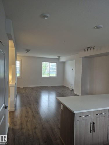 Wood-finish flooring, recessed lighting, track lighting, white walls, and a kitchen island with integrated cabinetry - Edmonton, AB - Indoor
