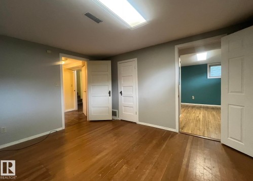 Wood-finish flooring throughout, light gray walls, white trim, and white paneled doors - 9828 84 Avenue Nw, Edmonton, AB - Indoor
