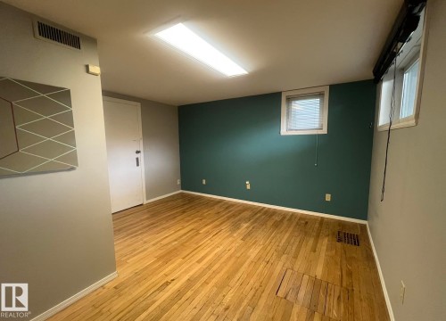 Wood-finish flooring, two windows with blinds, recessed ceiling light, and painted accent wall - 9828 84 Avenue Nw, Edmonton, AB - Indoor