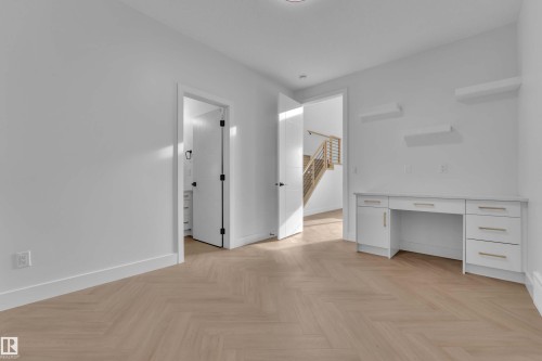 Herringbone wood-finish flooring, built-in desk with white cabinetry, gold-finish hardware, built-in floating shelves, and a contemporary staircase - 465 Crystal Creek Link, Leduc, AB - Indoor Photo Showing Other Room