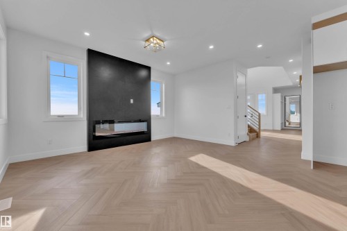 Herringbone pattern wood-finish flooring, recessed lighting, and a modern fireplace with a dark surround - 465 Crystal Creek Link, Leduc, AB - Indoor Photo Showing Other Room With Fireplace