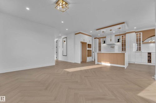 Herringbone wood-finish flooring, recessed lighting, and a modern kitchen featuring white and wood-finish cabinetry, a central island, and pendant lighting - 465 Crystal Creek Link, Leduc, AB - Indoor Photo Showing Kitchen