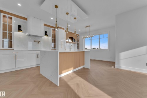 Contemporary kitchen featuring white cabinetry, a large center island with a waterfall countertop, and wood-finish flooring in a herringbone pattern - 465 Crystal Creek Link, Leduc, AB - Indoor Photo Showing Kitchen With Upgraded Kitchen