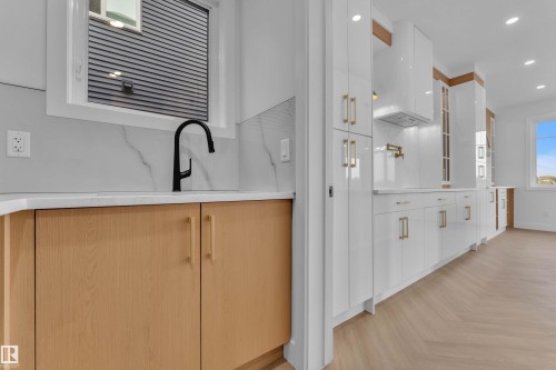 Modern kitchen featuring light wood-finish lower cabinetry, white upper cabinetry, and a white countertop - 465 Crystal Creek Link, Leduc, AB - Indoor Photo Showing Other Room