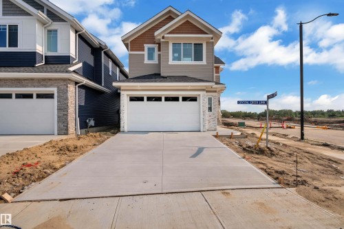 Two-story exterior with a two-car garage, concrete driveway, and stone facade accents - 465 Crystal Creek Link, Leduc, AB - Outdoor With Facade